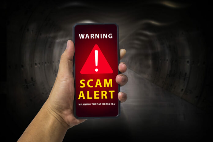 Man hand holding a mobile phone with red screen and warning icon with the text